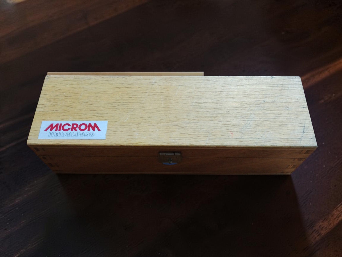 Closed wooden storage case with MICROM Heidelberg label and metal latch.
