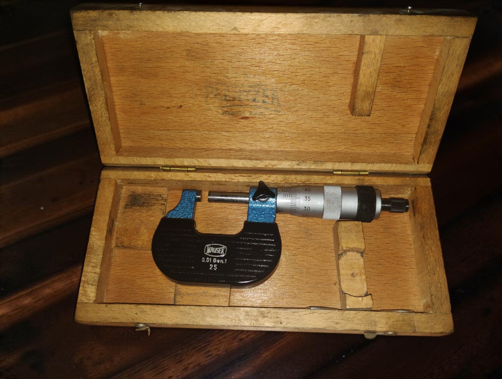 Vintage Mauser outside micrometer with a blue hammered finish and black frame beside its wooden case.
