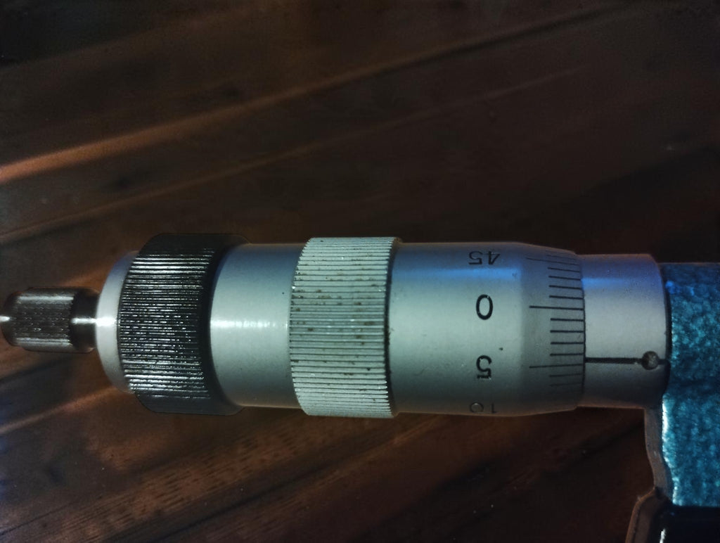 Close-up of the Mauser logo, 0.01 marking, and measuring spindle on the vintage outside micrometer.
