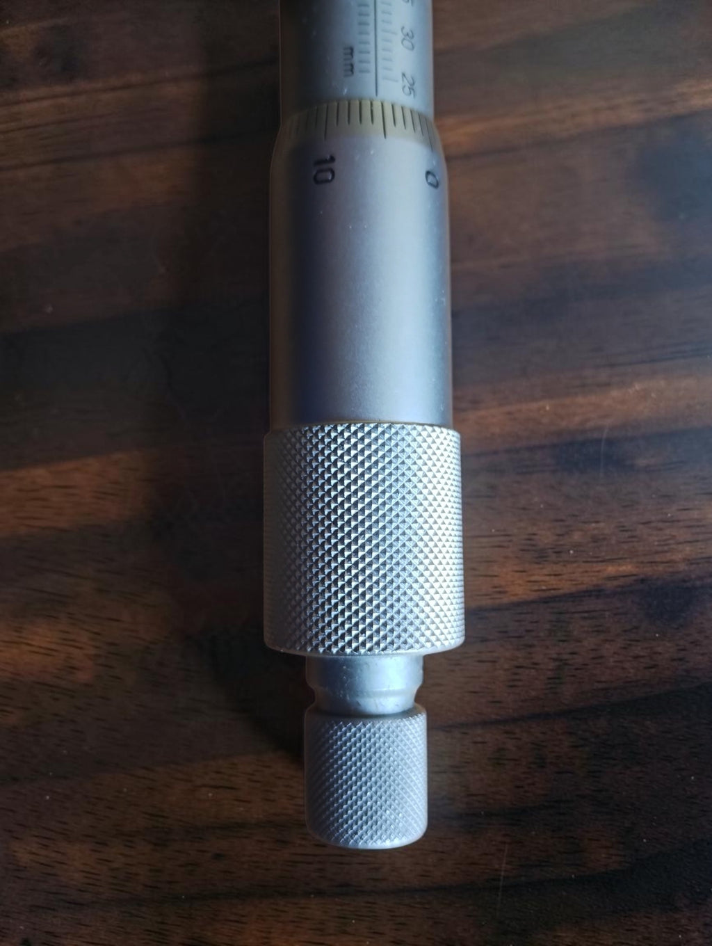 Close-up of the inside micrometer's knurled adjustment knobs and graduated thimble
