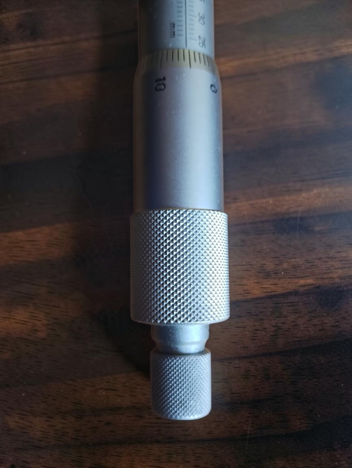 Close-up of the inside micrometer's knurled adjustment knobs and graduated thimble
