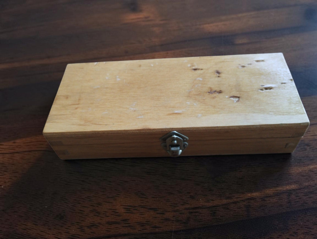 Closed wooden micrometer case with metal clasp, small dents, and storage marks
