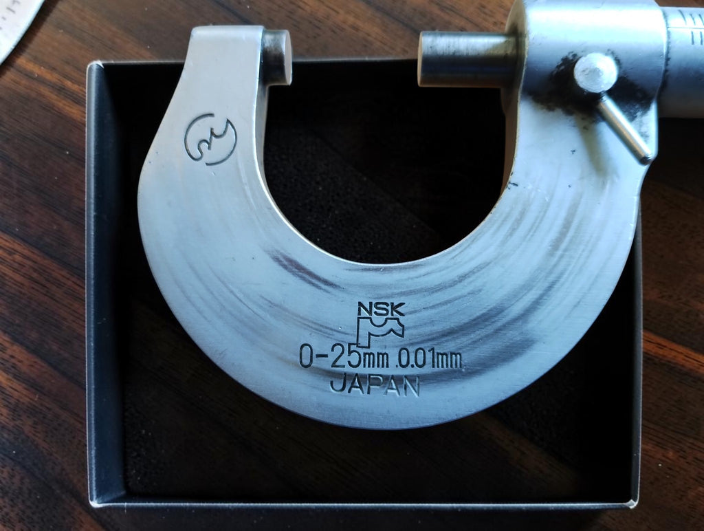 NSK micrometer frame marked Japan, 0–25 mm and 0.01 mm, showing scratches and wear.
