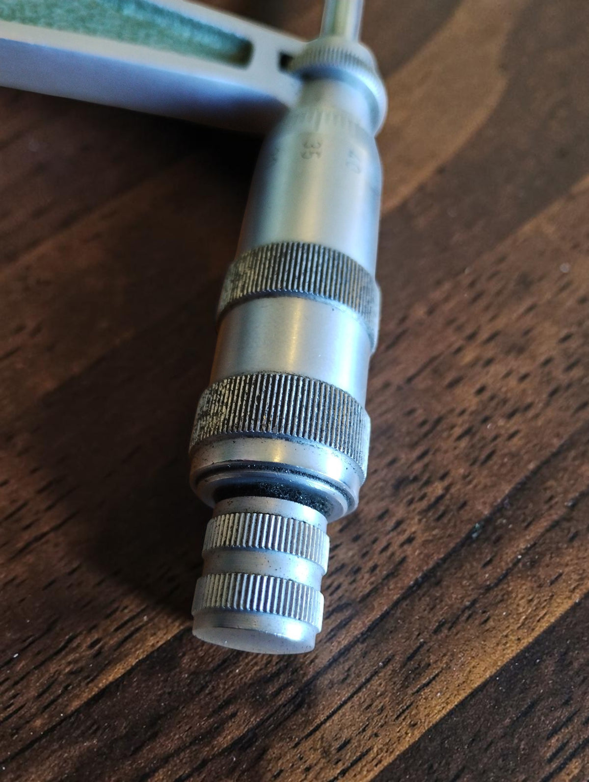 Close-up of the metal thimble and knurled adjustment mechanism on a vintage MAUSER outside micrometer
