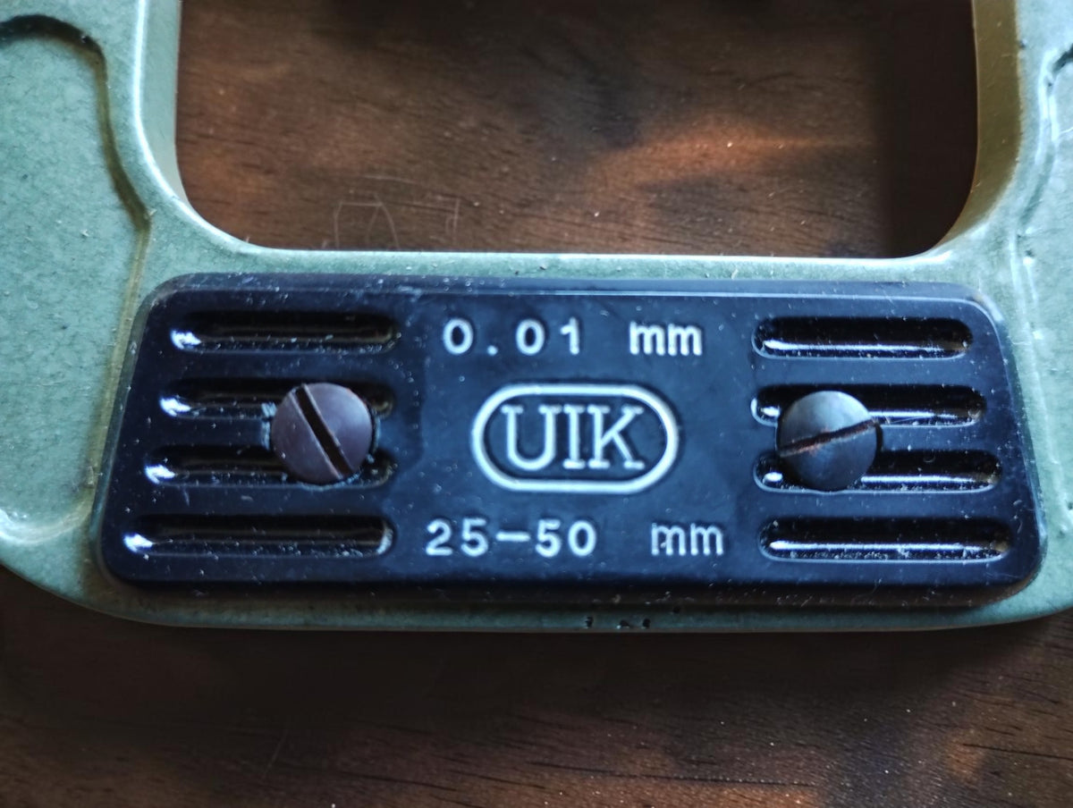 Close-up of the UIK nameplate showing the 25–50 mm measuring range and 0.01 mm graduations.

