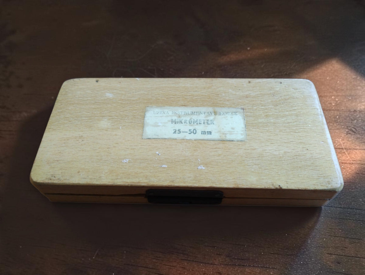 Closed wooden micrometer case with a paper label showing the 25–50 mm measuring range.
