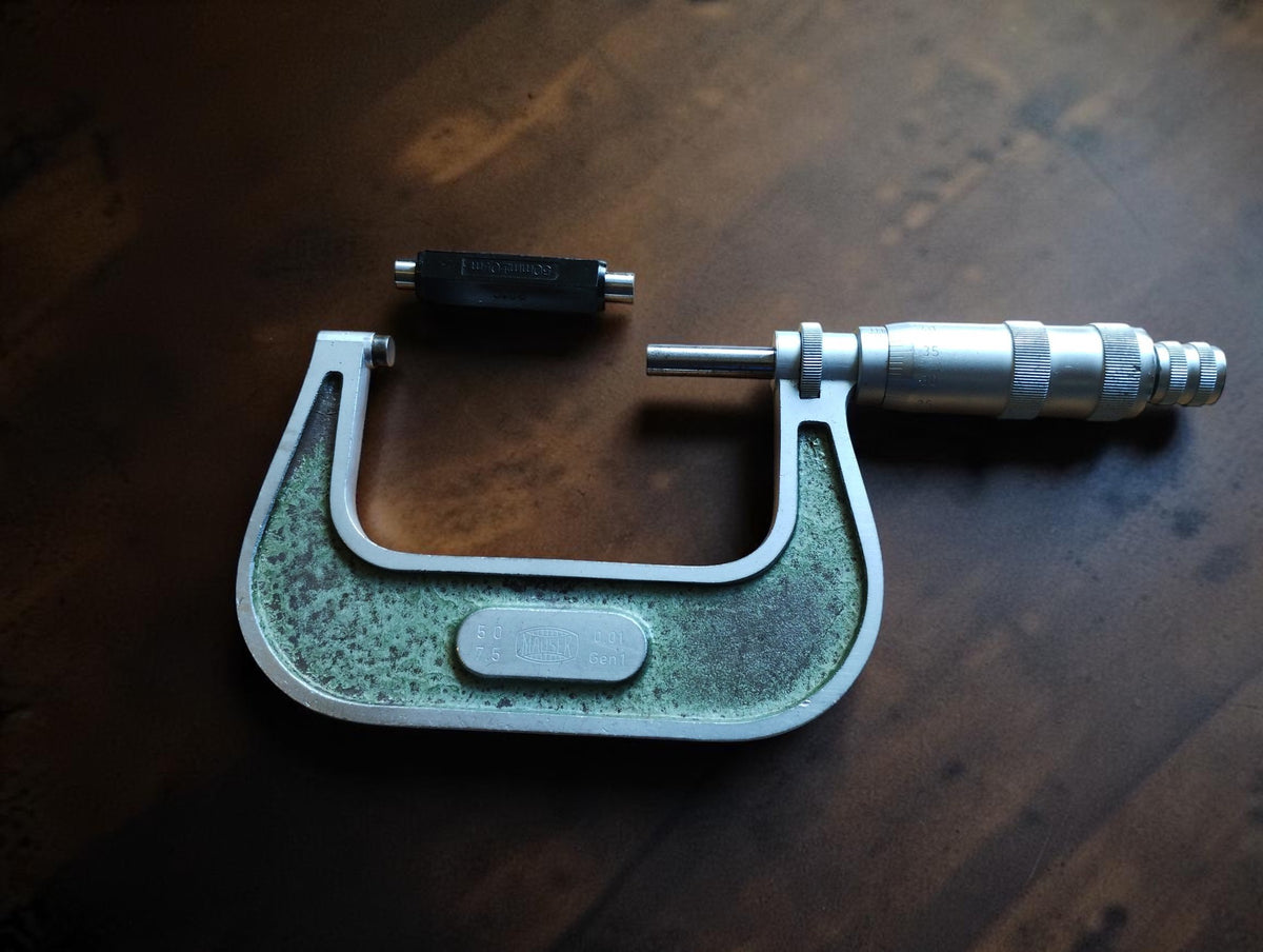 MAUSER outside micrometer with green frame and separate setting standard on a wooden surface
