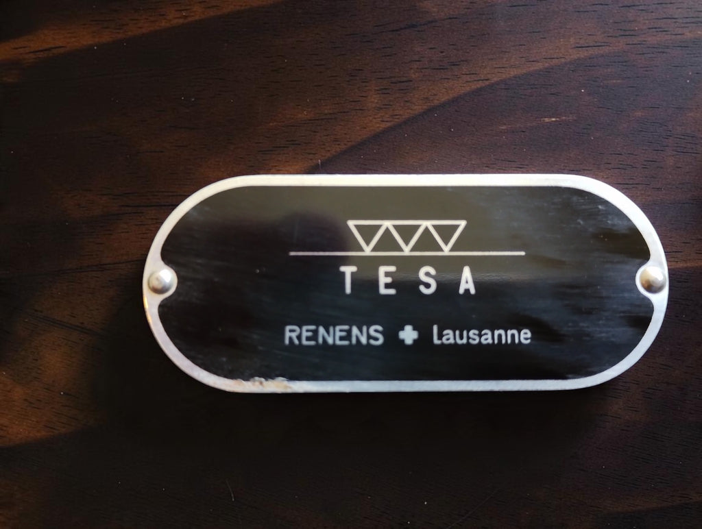 Close-up of the riveted TESA nameplate with three triangle symbols and Renens Lausanne lettering.
