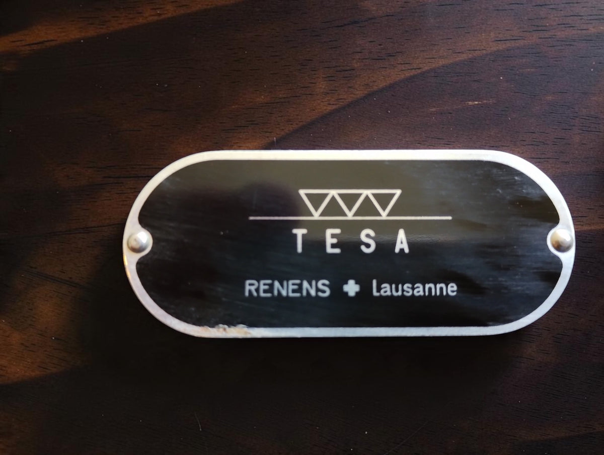Close-up of the riveted TESA nameplate with three triangle symbols and Renens Lausanne lettering.
