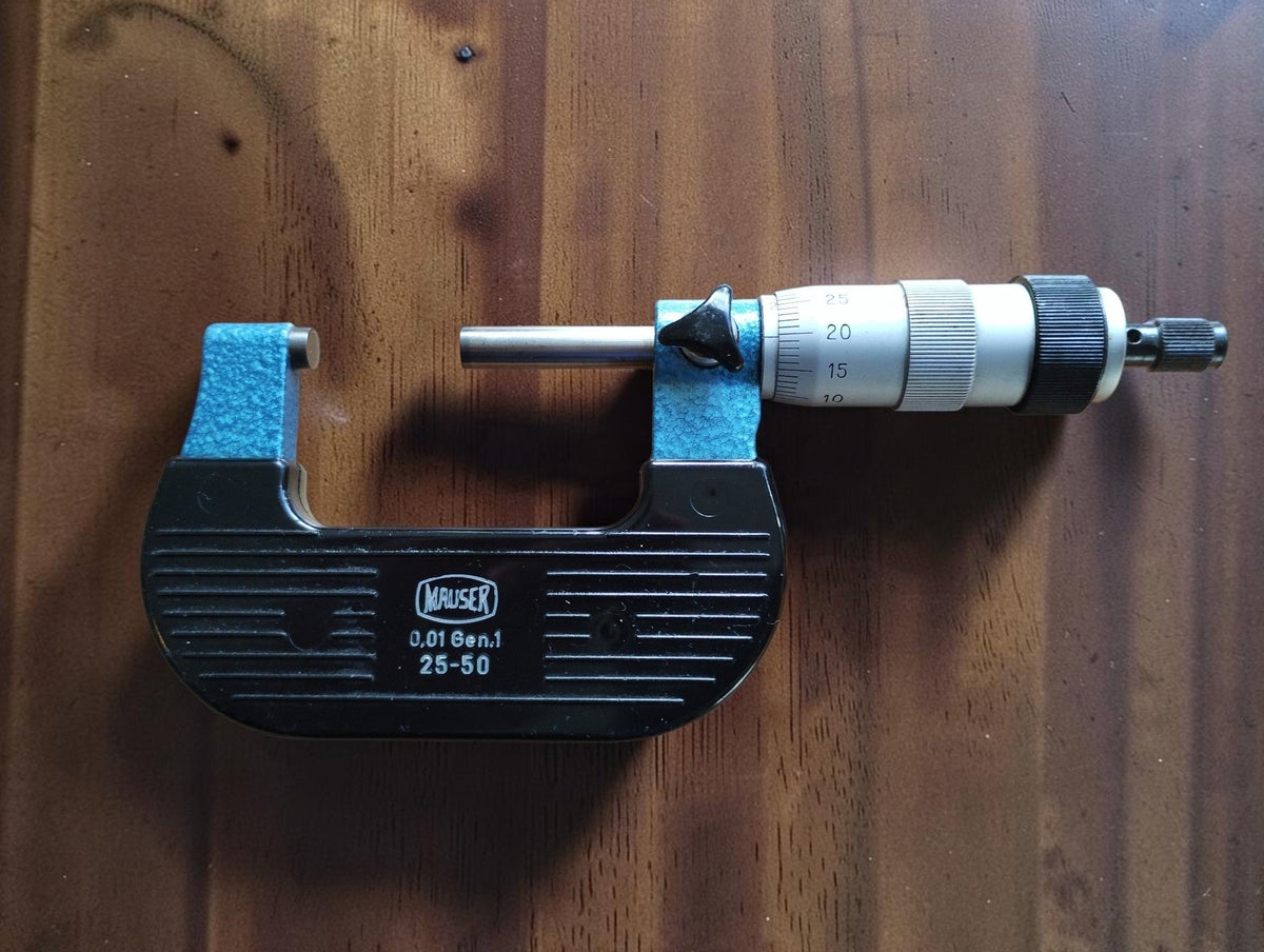 Mauser 25–50 mm outside micrometer with blue frame, black ribbed grips, graduated thimble and ratchet knob.
