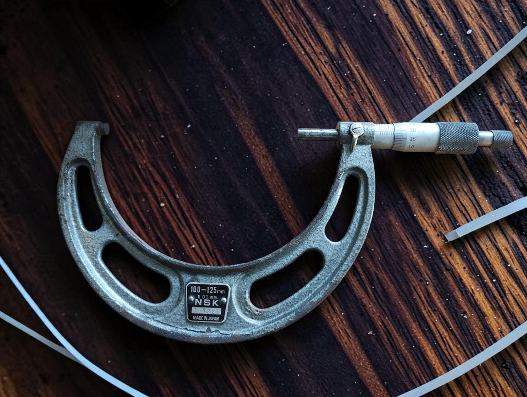 NSK 100–125 mm outside micrometer showing the open frame, measuring spindle, graduated thimble and visible wear.
