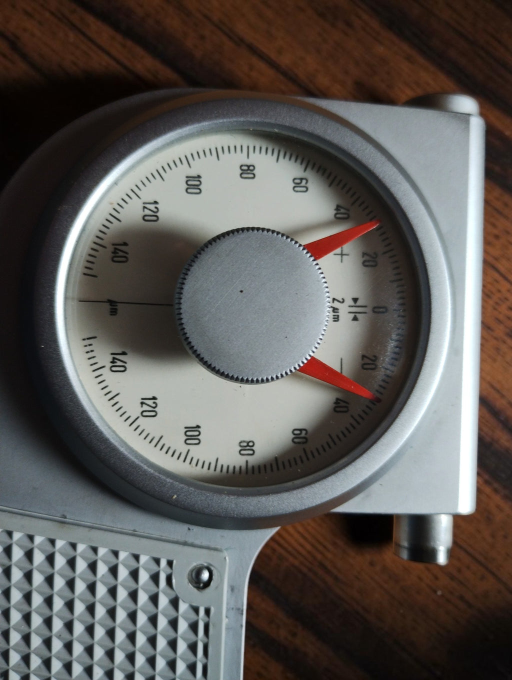 Close-up of the indicating micrometer dial with graduated scale and red limit markers.
