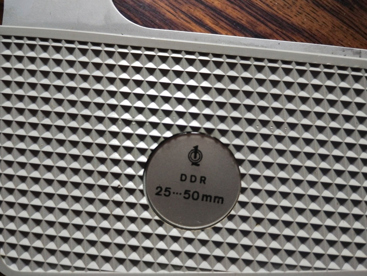 Close-up of the DDR marking and 25–50 mm measuring range on the micrometer frame.
