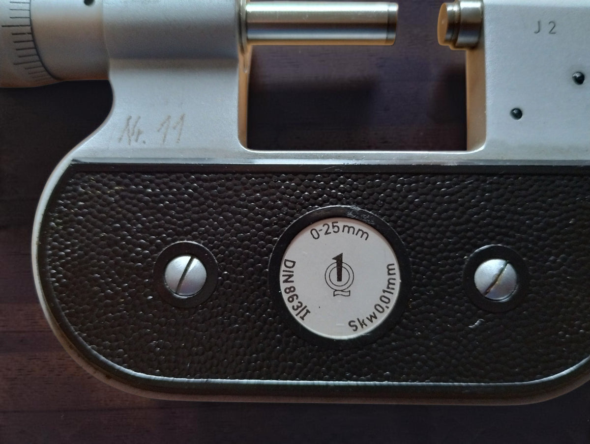 Rear specification badge showing the 0–25 mm range, DIN 863/III marking and 0.01 mm scale division.
