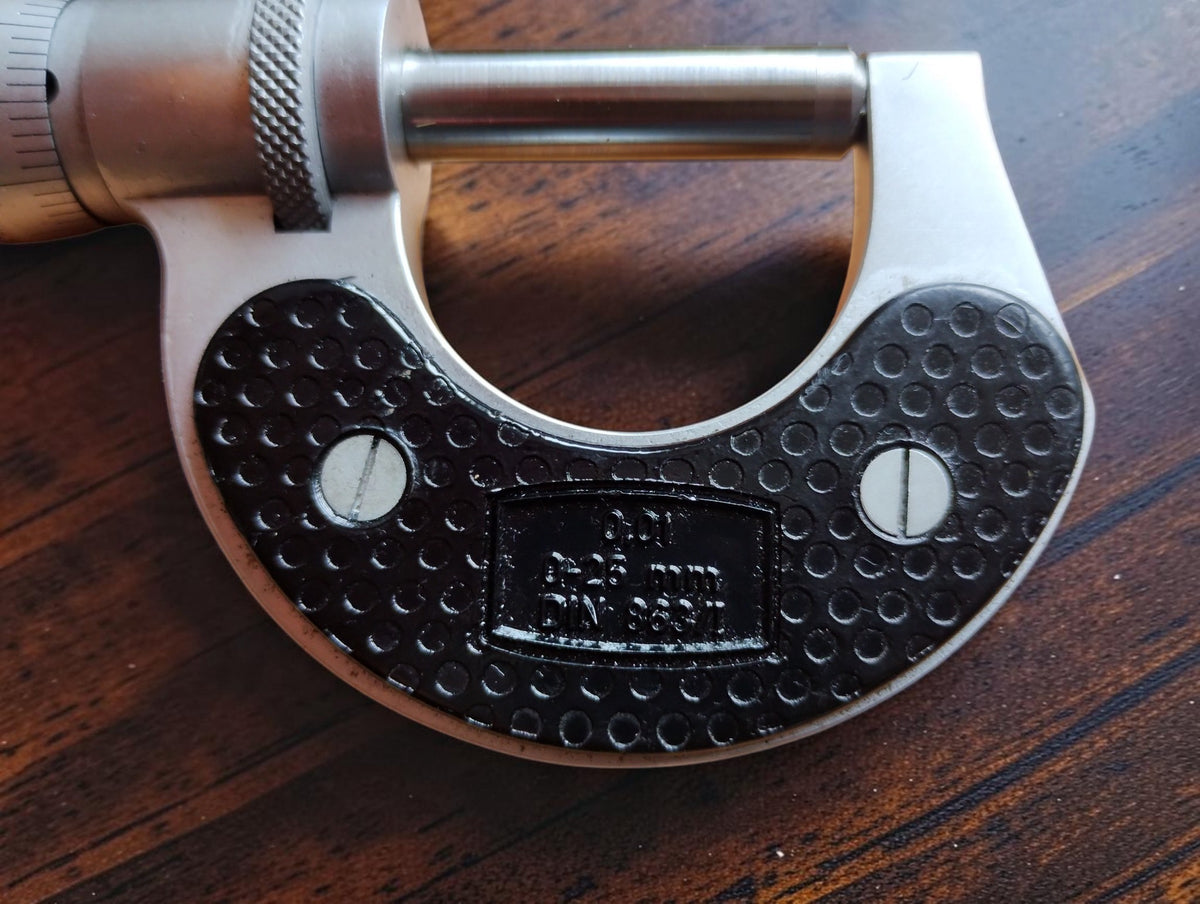 Detail of the MATRA outside micrometer with textured black grip plates and engraved measurement markings
