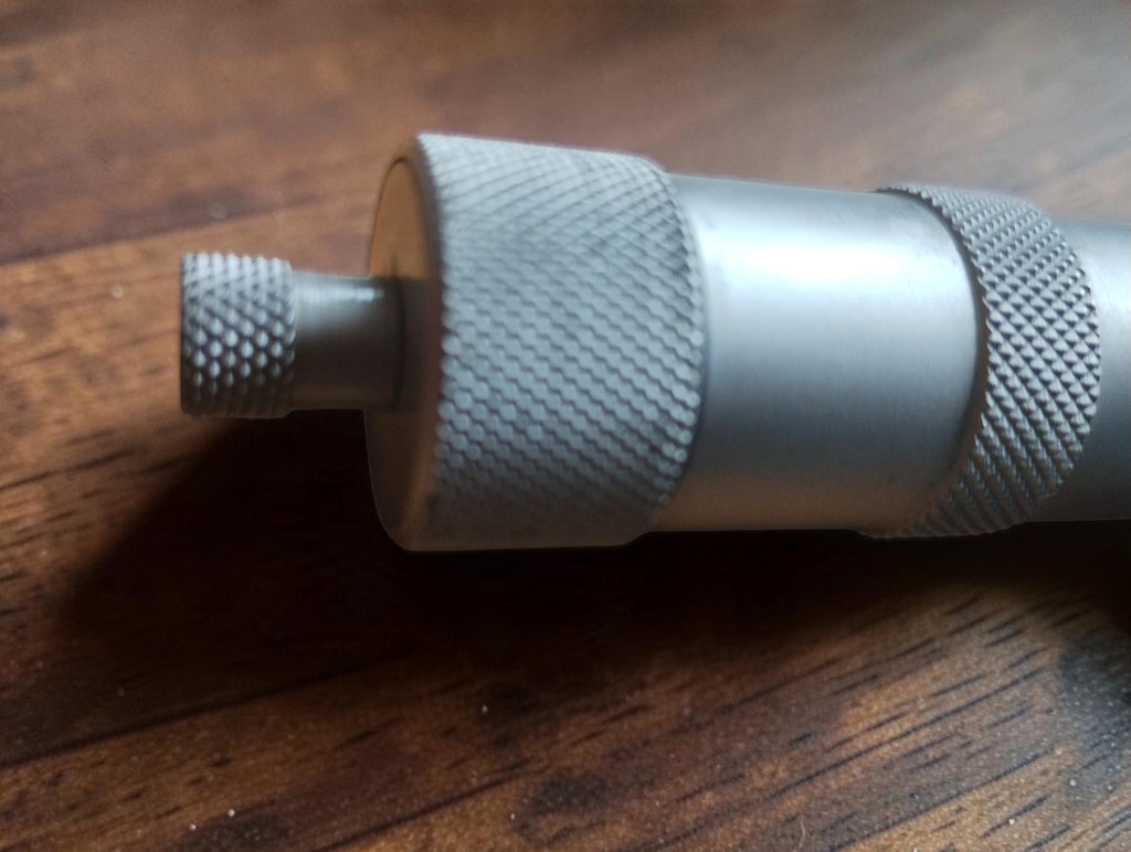 Close-up of the knurled end knob and silver-colored thimble on the vintage Massi micrometer.

