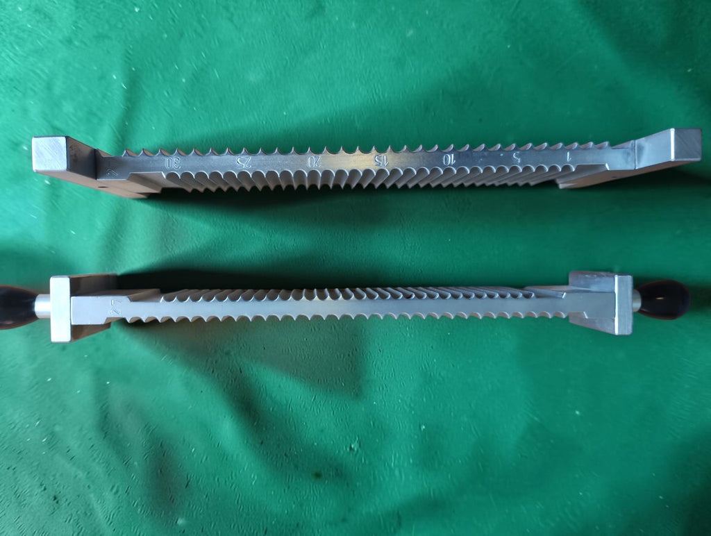Side view of two metal pill-making components showing semicircular grooves, engraved markings and dark handles.
