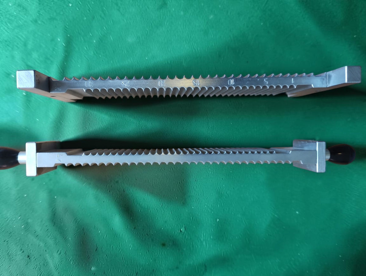 Side view of two metal pill-making components showing semicircular grooves, engraved markings and dark handles.
