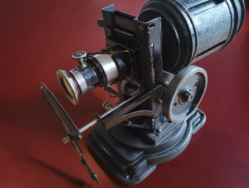 Antique VEDES projector showing the lens, slide holder, drive wheel and exposed hand-operated mechanism.
