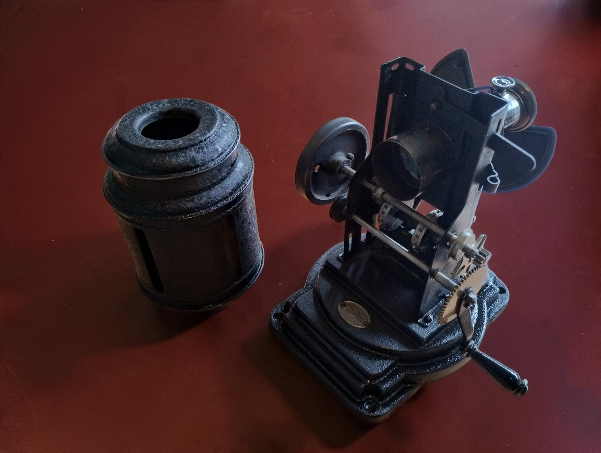 Antique VEDES projector with its cylindrical housing removed and placed beside the exposed mechanism.
