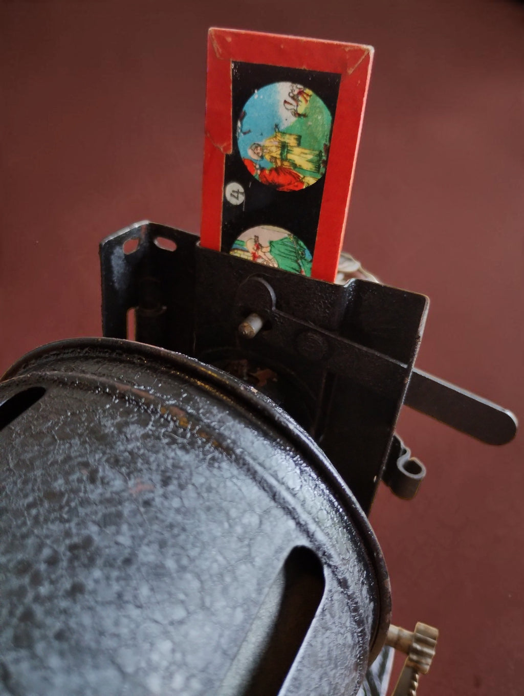 Red-framed illustrated glass slide in the VEDES projector's holder; the seller reports glass damage to this slide.
