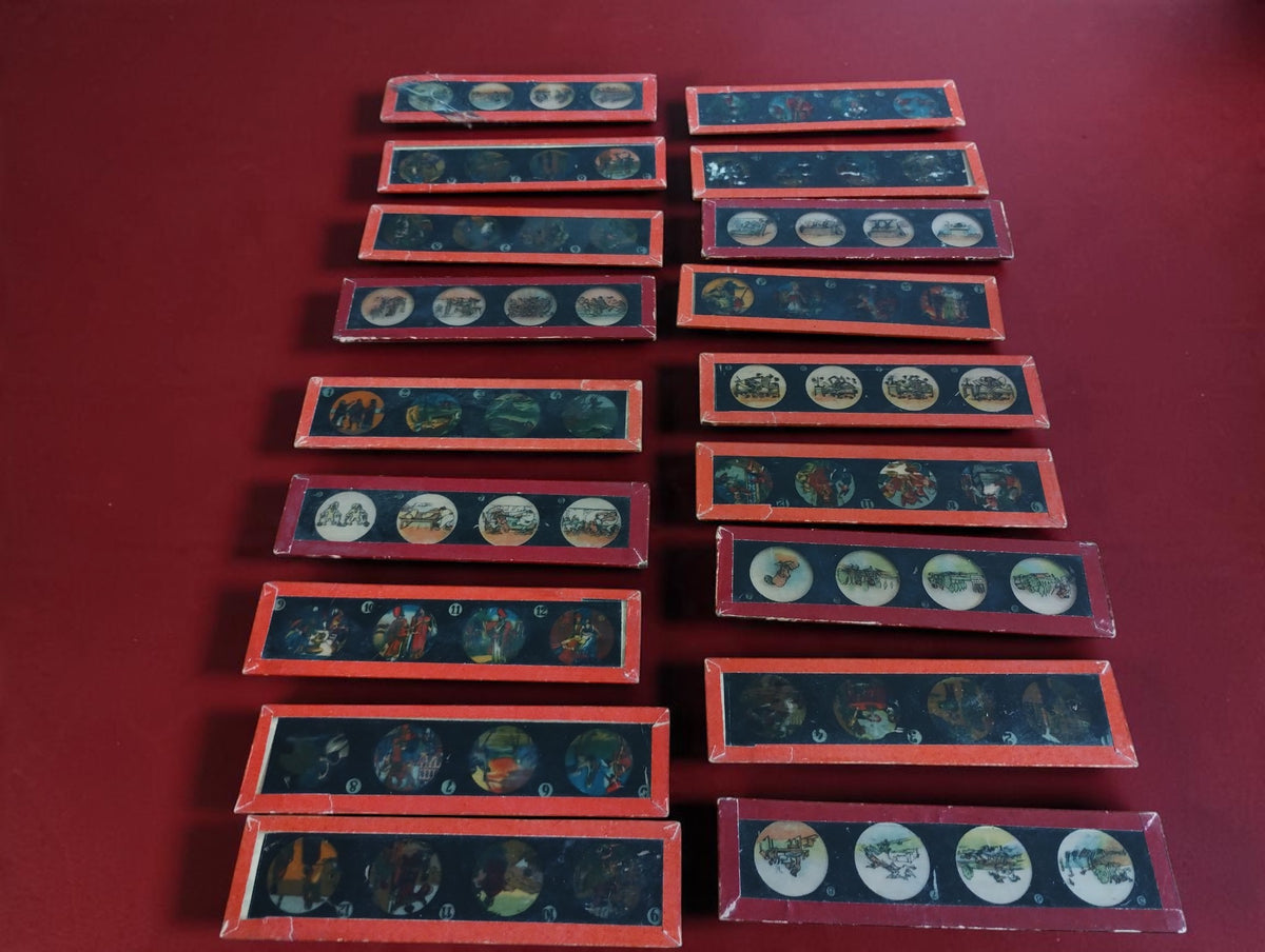 Collection of red-framed illustrated magic lantern glass slides arranged in two columns on a red surface.
