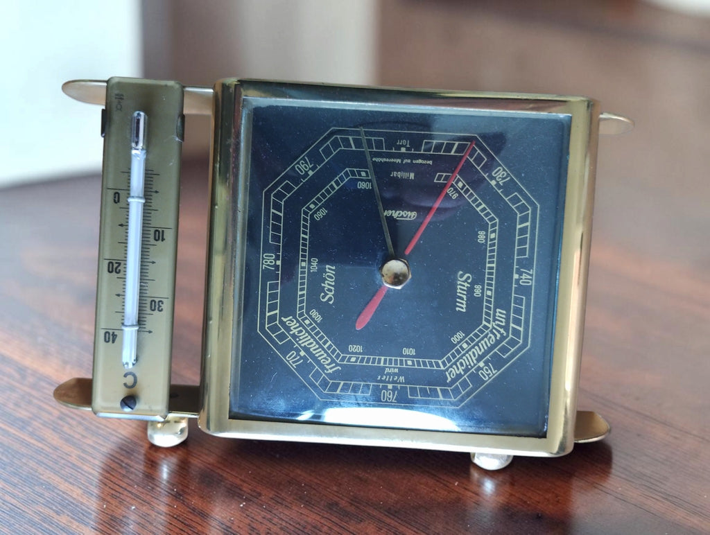 Fischer tabletop weather station photographed upside down, showing the barometer dial and glass Celsius thermometer.
