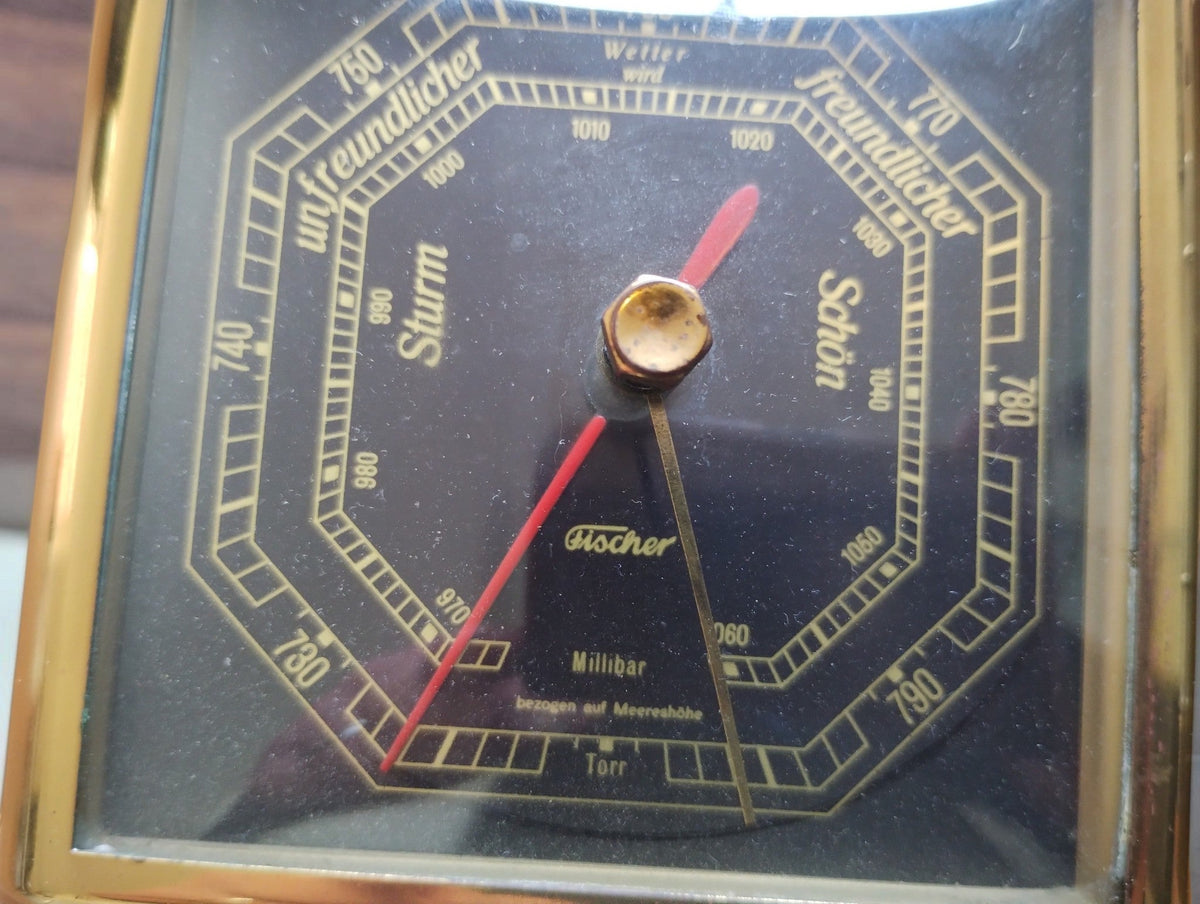 Close-up of the Fischer barometer dial with German weather terms, octagonal scales, red needle and gold-tone reference pointer.
