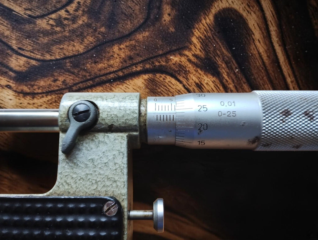 Detail of the micrometer graduations, locking lever and measuring spindle on the green hammer-finish frame.
