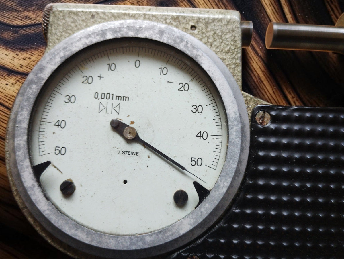 Close-up of the micrometer dial marked 0.001 mm and 7 Steine, showing the pointer and scale.
