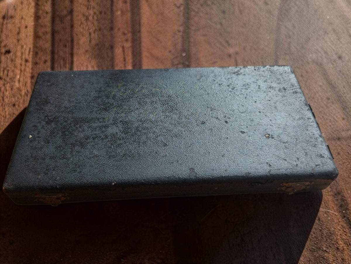 Closed dark micrometer case showing surface wear and marks on the exterior.
