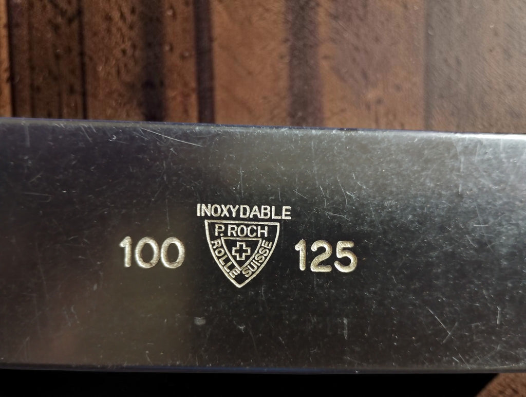 Close-up of the P. Roch Rolle Suisse shield logo, INOXYDABLE inscription and 100–125 mm range markings.

