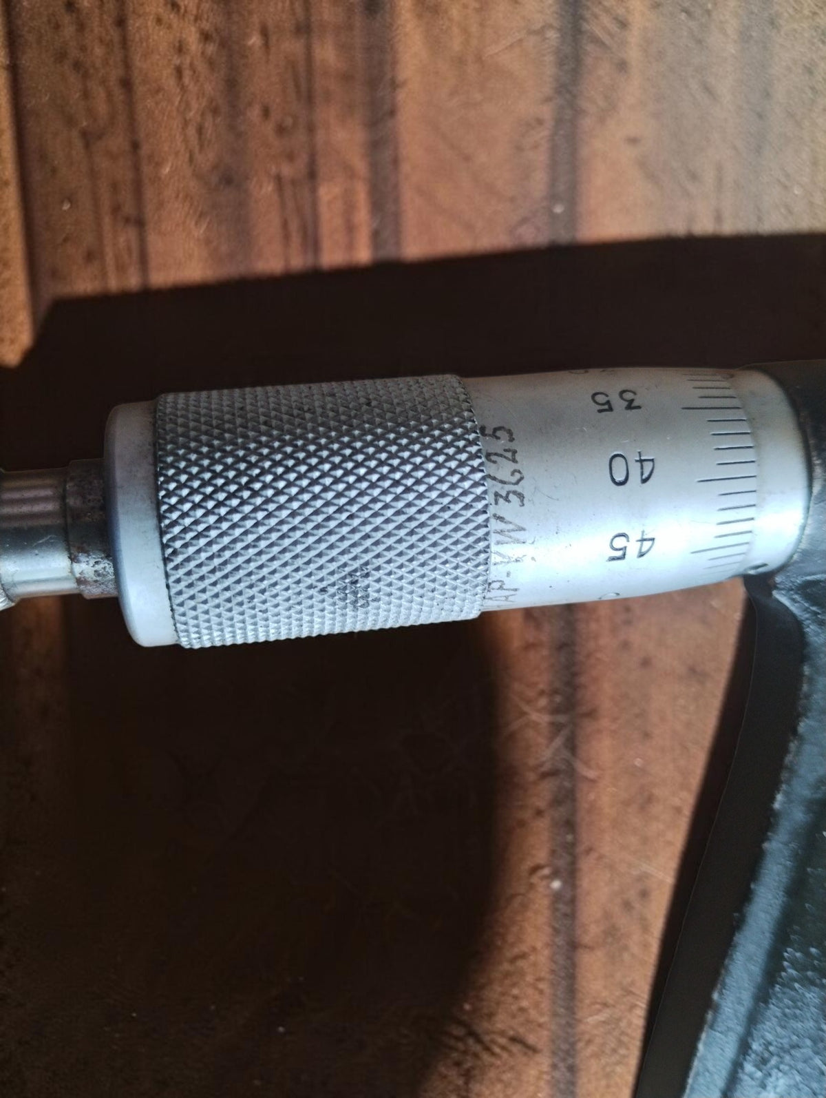 Close-up of the micrometer's knurled thimble, numbered scale and scratched identification marks.
