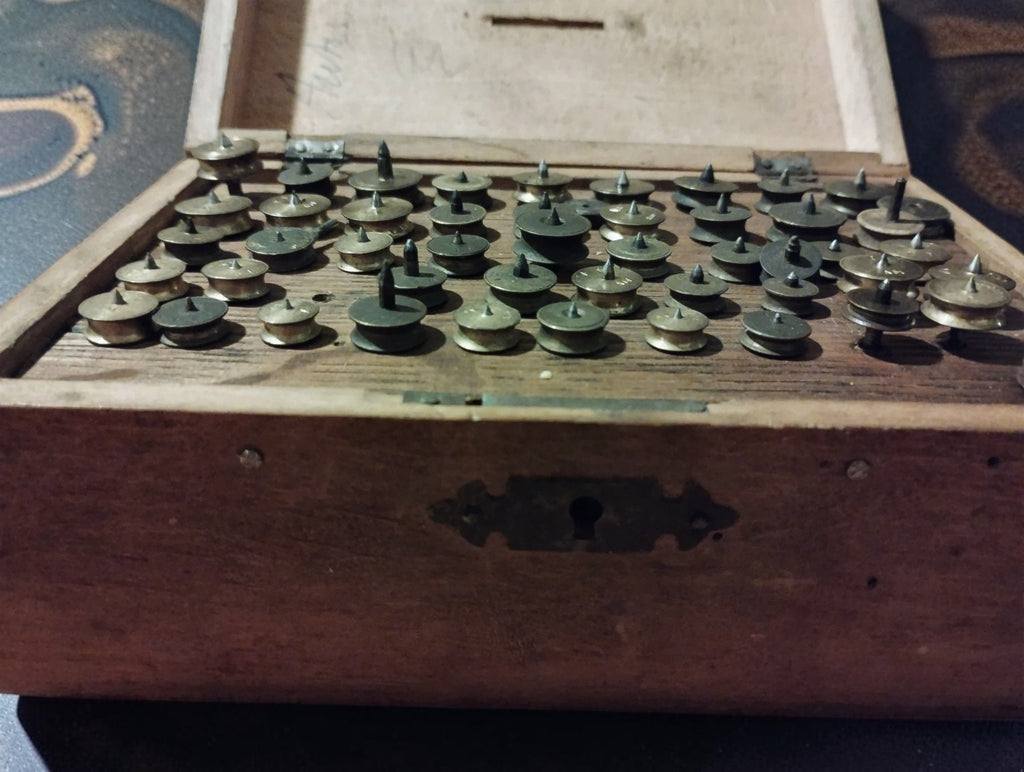 Front view of the open lantern runner case, showing the decorative metal keyhole plate and rows of watchmaking tools.
