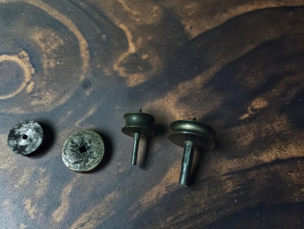 Four loose components from the antique lantern runner set, showing metal discs, shafts, patina and surface oxidation.
