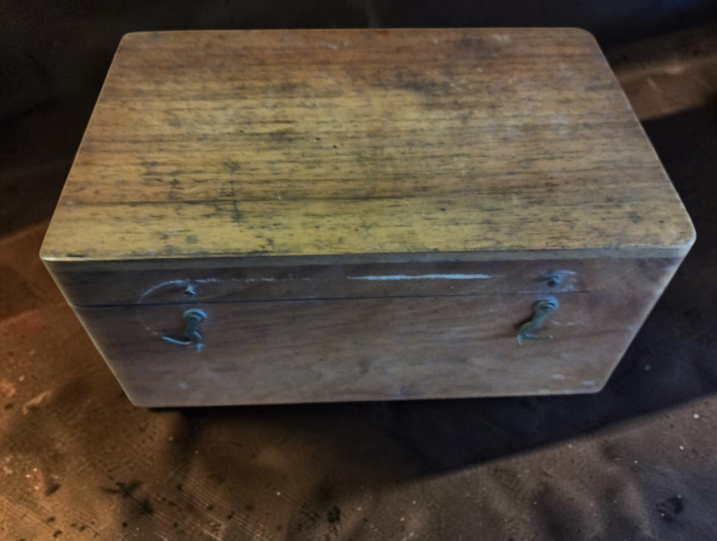 Front view of the closed wooden topping tool cutter case, showing its worn patina and two fastening hooks.
