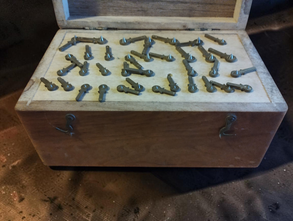 Open wooden case showing antique rounding-up cutters mounted on individual steel shafts in a fitted wooden tray.
