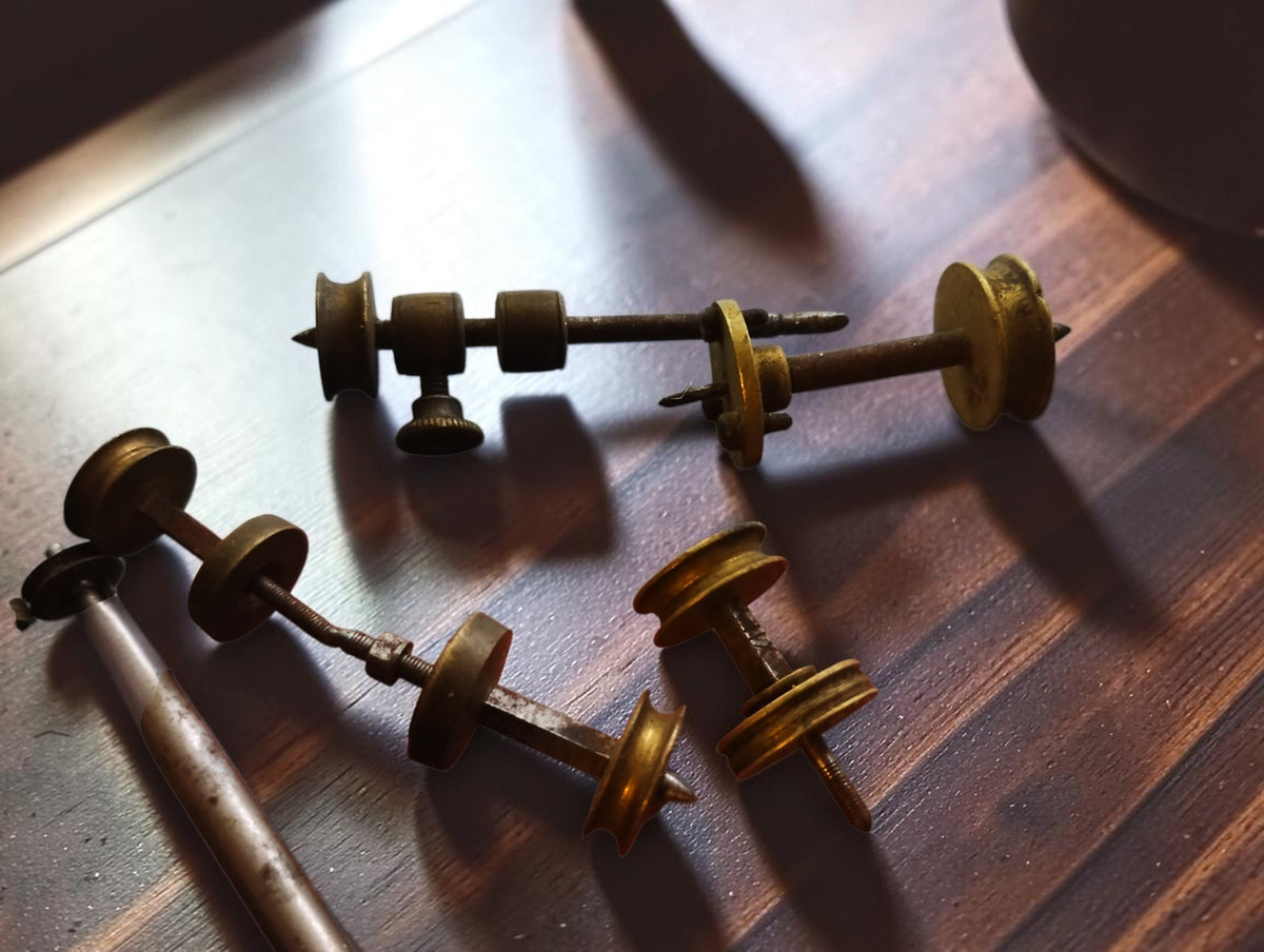 Close-up of antique Jacot-tool runners with brass pulleys, steel shafts and a knurled adjustment screw
