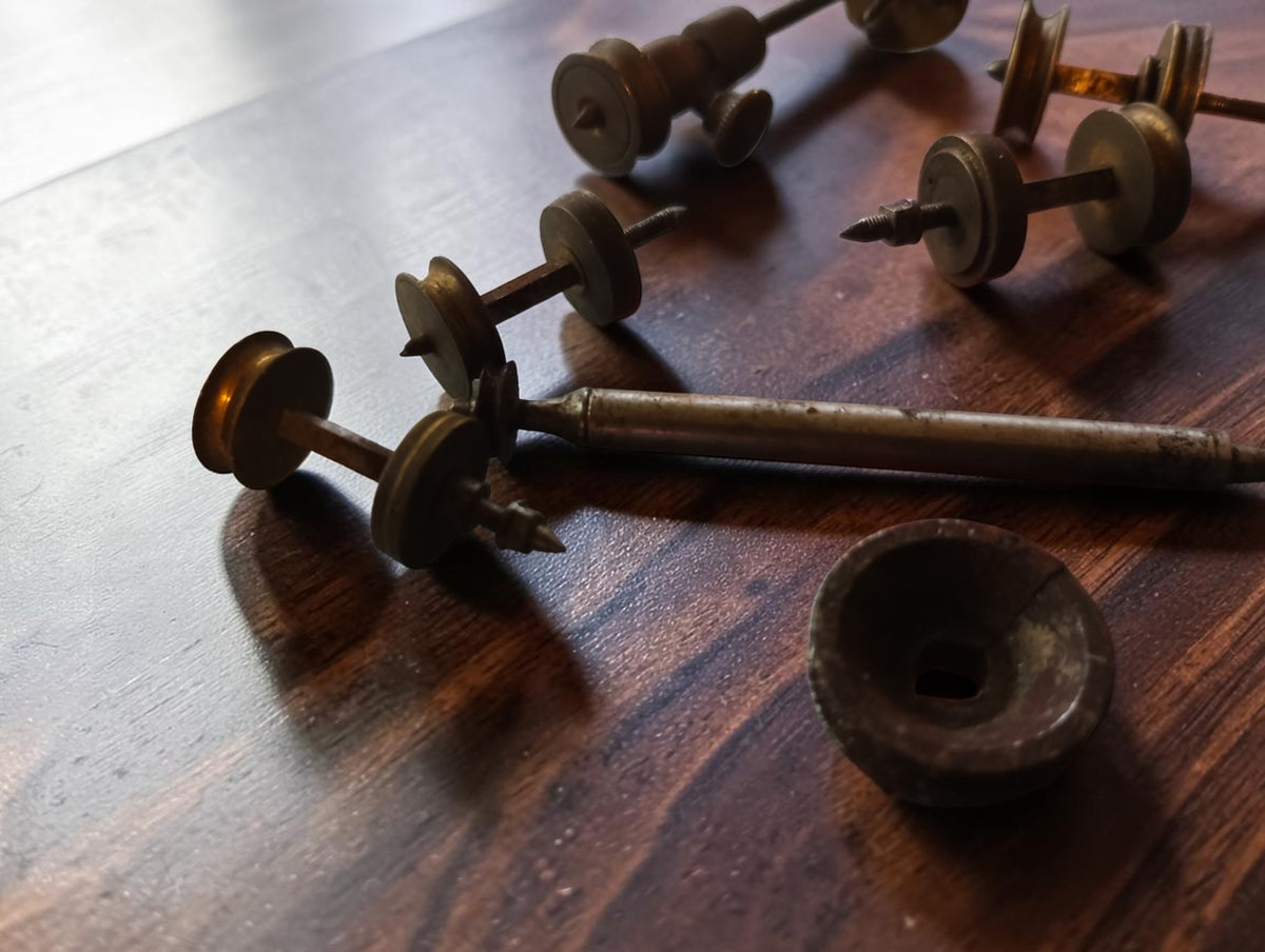 Close-up of antique watchmaking shafts, brass pulleys and a loose disc with visible age and wear
