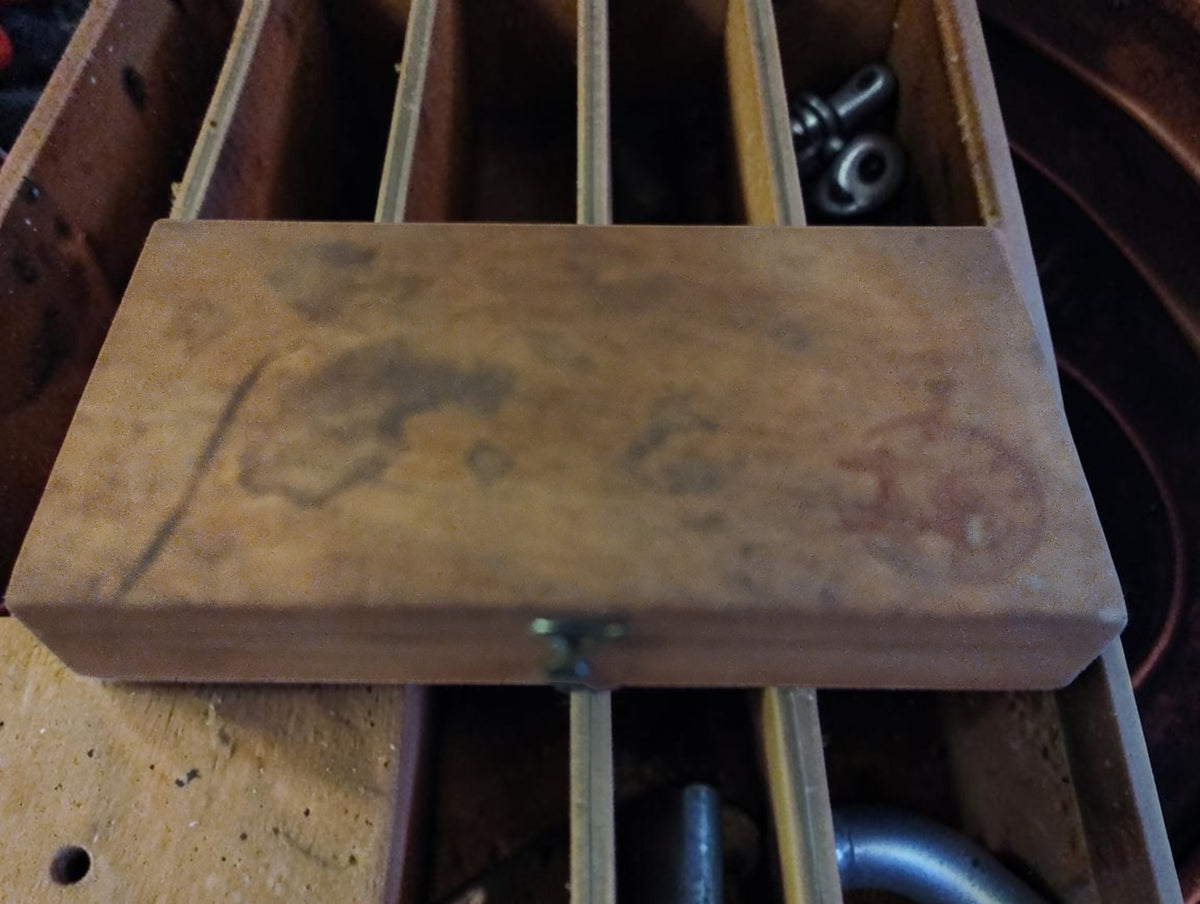 Closed wooden Ludwig & Fries assortment box with a faded circular stamp, front clasp, and visible wear.
