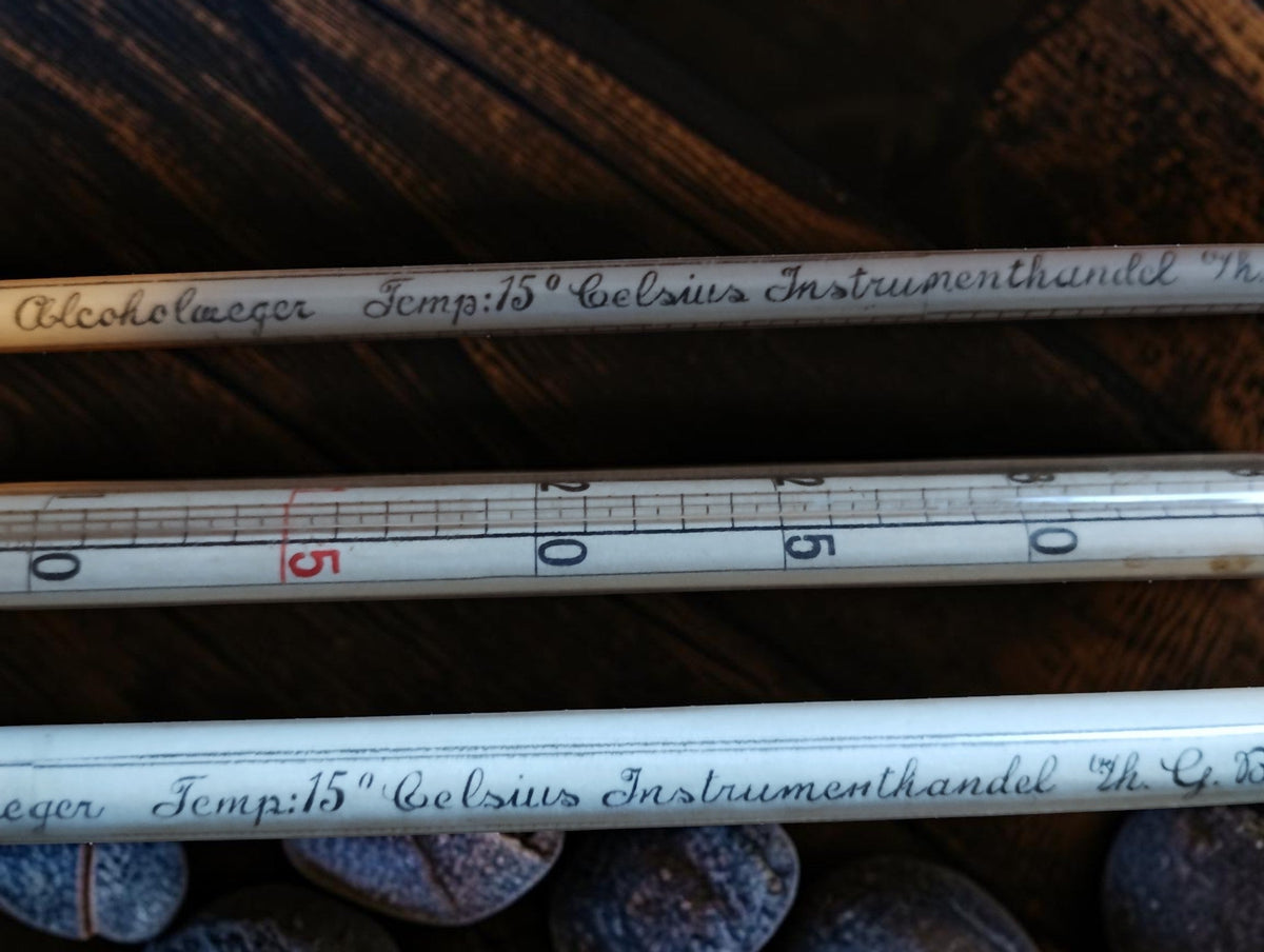Thermometer scale beside the handwritten Rijks Honderddeelige Alcoholweger inscriptions on the hydrometers.
