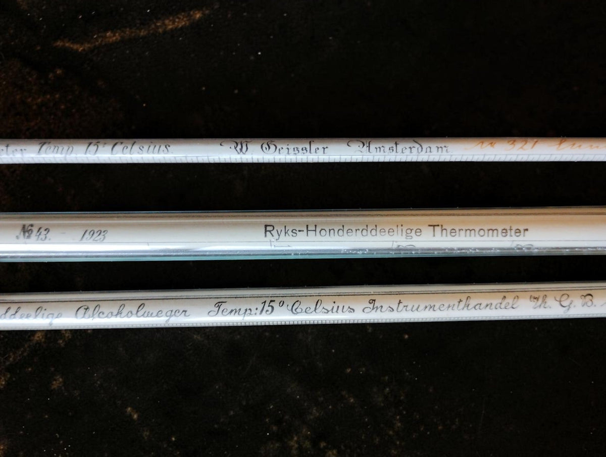Detail of the Rijks-Honderddeelige Thermometer inscription and handwritten markings on the glass hydrometers.
