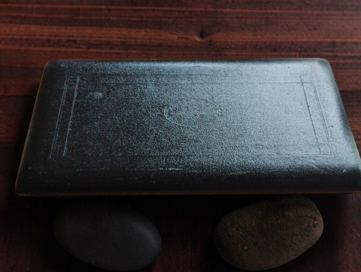 Closed black drafting instrument case with a textured surface, embossed border decoration and an oval PRÄZISION emblem.
