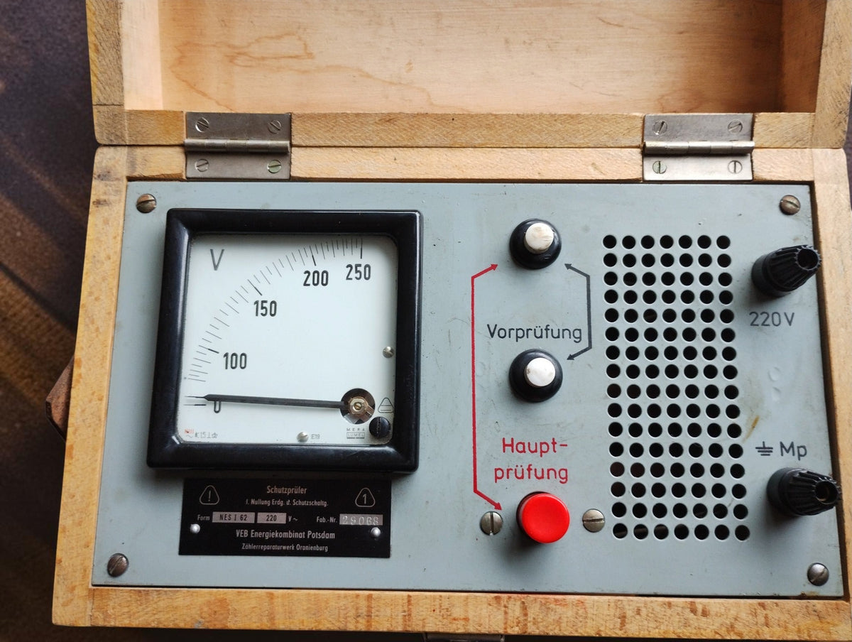 NES I/62 control panel with analog voltmeter, Vorprüfung controls, red Hauptprüfung button, and connection terminals.
