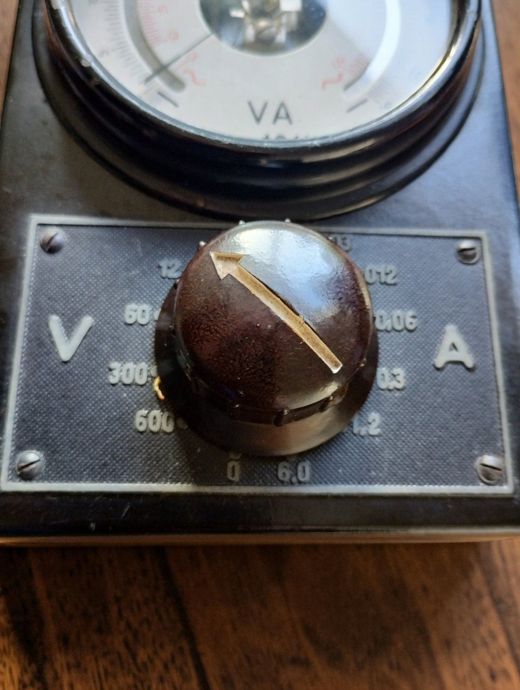 Close-up of the brown rotary range selector with arrow indicator and voltage and current markings
