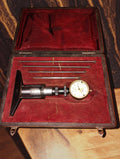 Vintage depth micrometer with dial indicator and four measuring rods in a red-lined storage case
