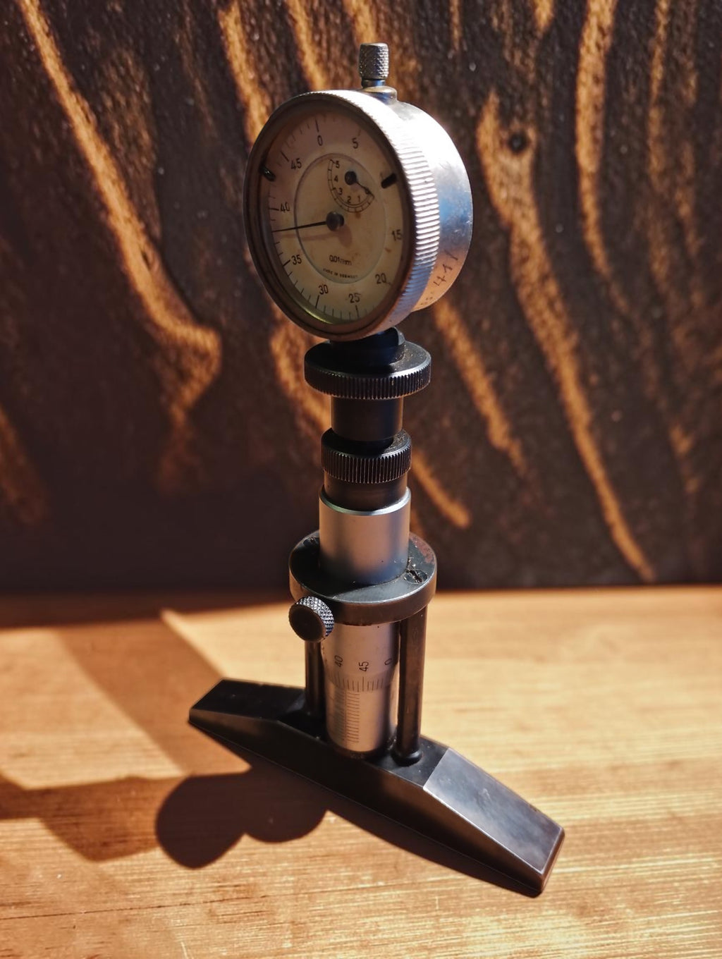 Vintage depth micrometer standing upright, showing the dial indicator, adjustment rings and measuring bridge

