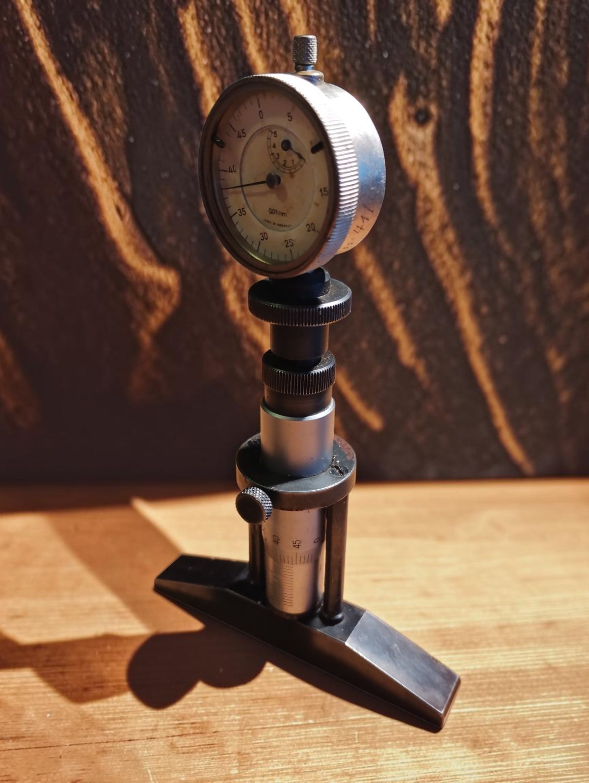 Vintage depth micrometer standing upright, showing the dial indicator, adjustment rings and measuring bridge
