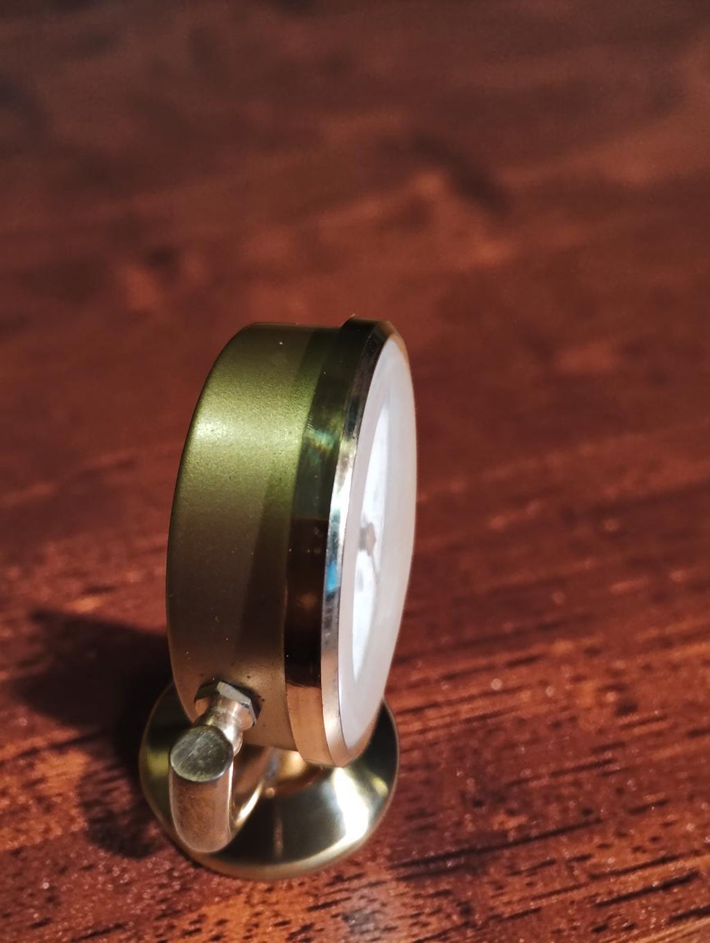 Side view of the vintage brass desk thermometer showing the case depth, pivot and pedestal base.
