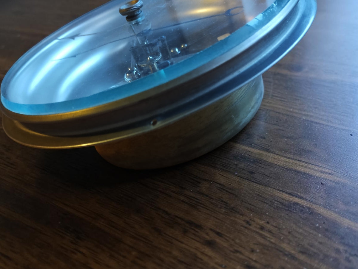 Close-up of the barometer's glass edge, metal bezel and projecting rear housing.
